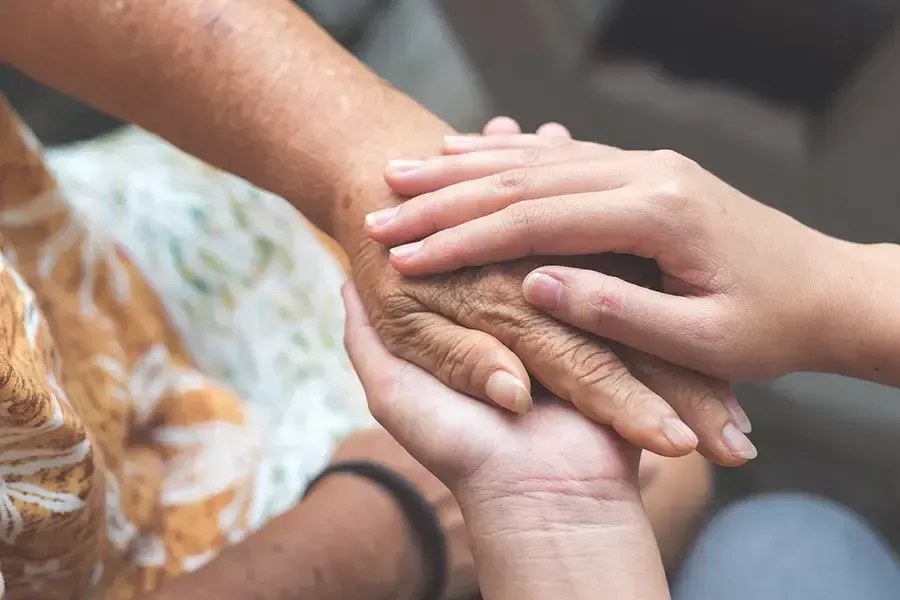 Holding the hands of another person comforting them