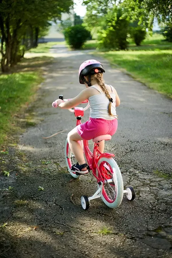 Girl riding a pink bike with helmet on