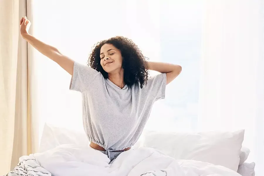 Lady stretching in bed as she wakes up