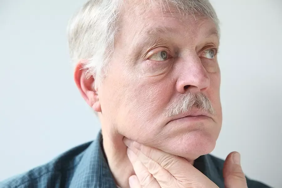 man feeling of his throat with one hand