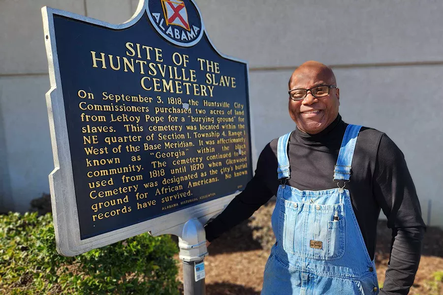 William Hampton stands next to historical sign.