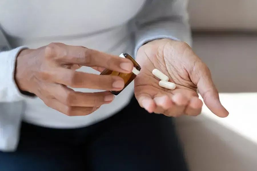 Someone getting two pills out of a prescription bottle