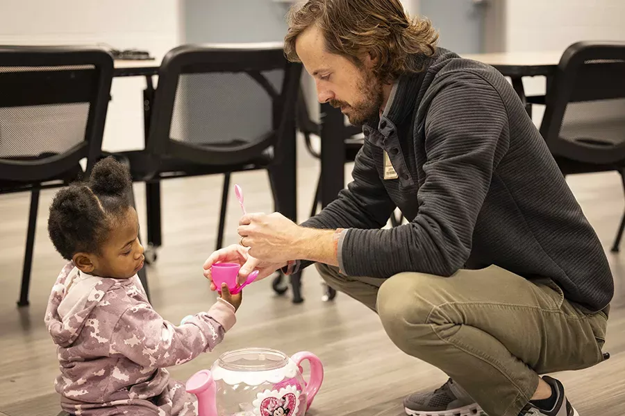 Community Health Initiative Project Coordinator John Simms, right, has a pretend tea party with Meleah, a 3-year-old who receives autism support services from The Arc.