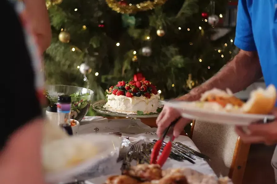 Man filling his plate with sweets and a Christmas tree in the background