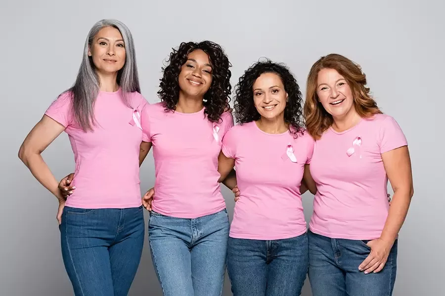 Four ladies smile in their pink shirts with pink breast cancer awareness ribbons on in honor of Breast Cancer Awareness month.