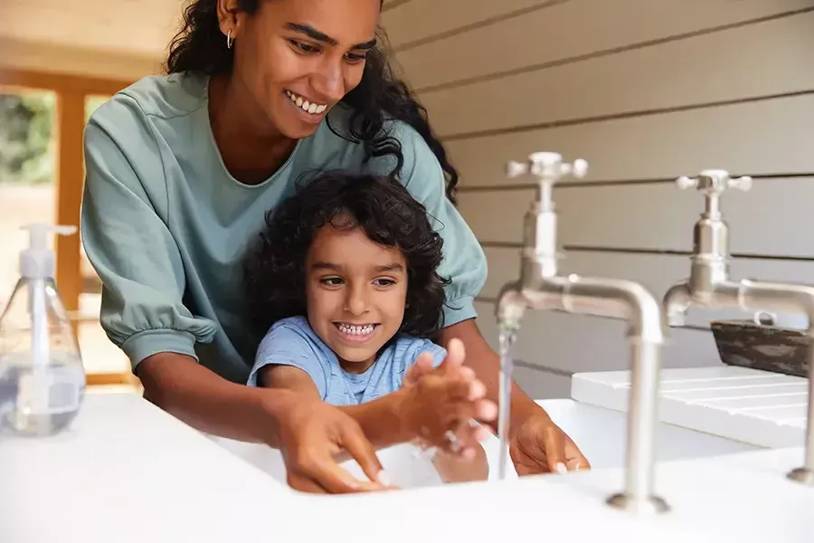 Mom helps daughter wash hands